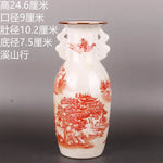 Un vase en porcelaine blanche décoré de motifs paysagers rouges, orné de personnages et de bâtiments traditionnels chinois, offrant une esthétique traditionnelle et élégante.