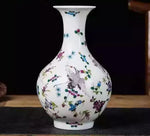 Vase en porcelaine blanc avec des motifs colorés de fleurs et d'oiseaux.