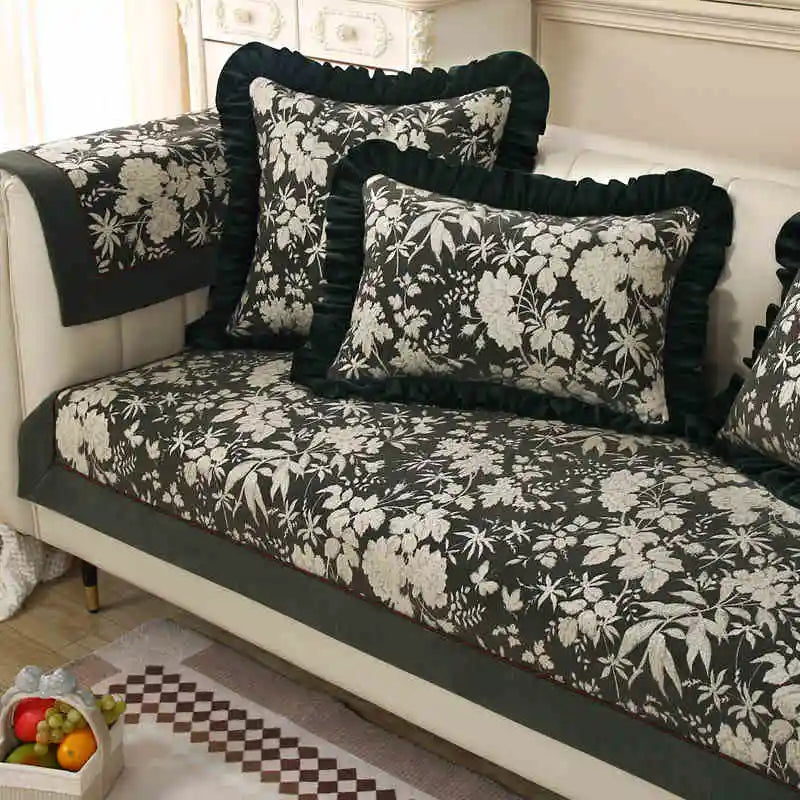 Ensemble de canapé et coussins noirs et blancs avec un motif floral décoratif dans un intérieur élégant et chaleureux.