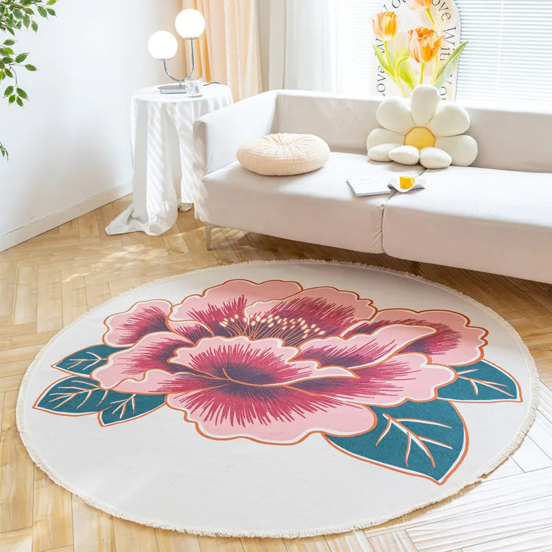 Un tapis rond décoratif avec un motif floral aux couleurs vives, posé dans un salon lumineux avec des meubles blancs et des touches végétales.