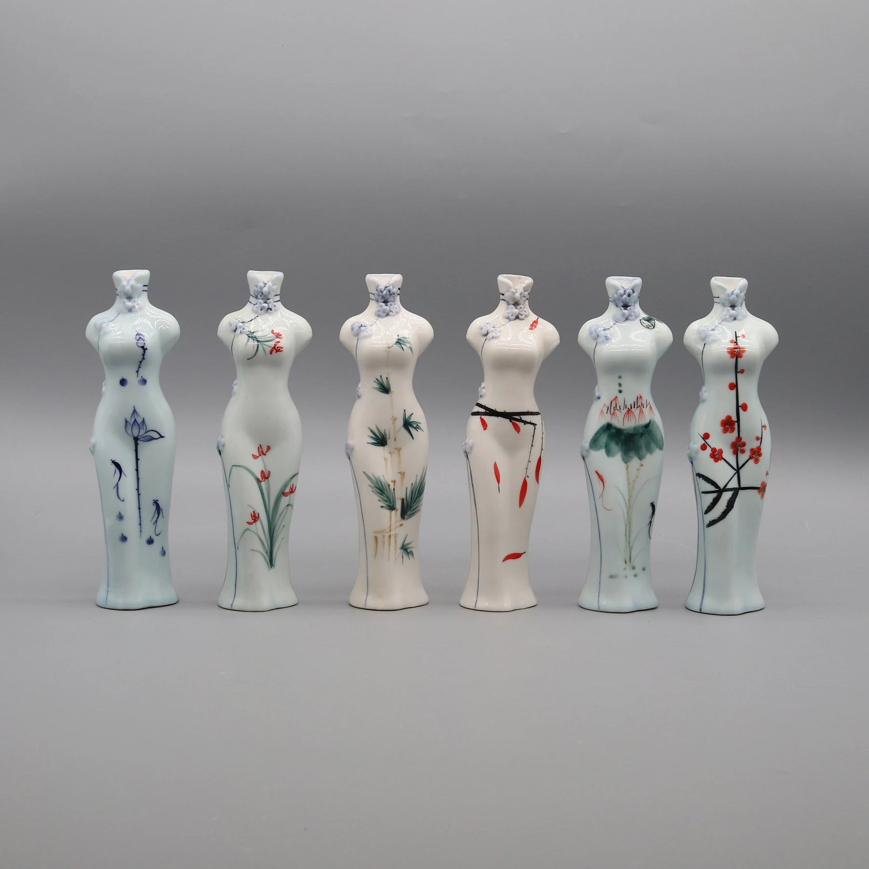 Une série de vases décoratifs en céramique blanche, chacun orné de délicats motifs floraux peints à la main, créant une présentation harmonieuse et élégante.