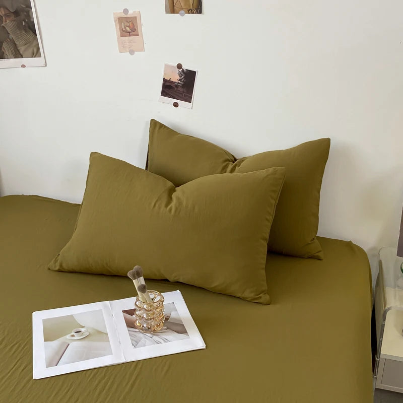 Une chambre accueillante avec des coussins confortables sur un lit vert olive, entourée de décoration murale et de Polaroids.