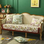 Le canapé en bois sculpté est recouvert de coussins motif feuillage, donnant une atmosphère chaleureuse et naturelle à cet espace de salon.