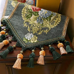 Un magnifique châle orné de motifs floraux et de pompons décoratifs, offrant une touches de couleurs chaudes et élégantes.