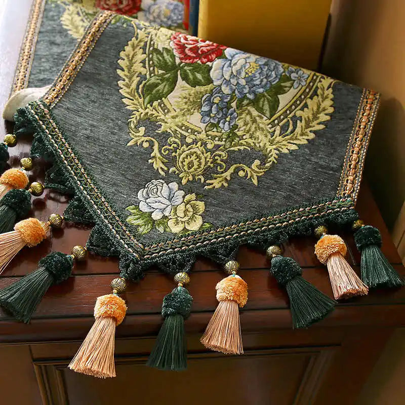 Un magnifique châle orné de motifs floraux et de pompons décoratifs, offrant une touches de couleurs chaudes et élégantes.