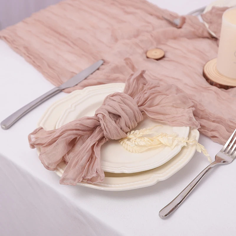 Une élégante configuration de table avec une nappe rose pâle, des assiettes blanches et des accessoires décoratifs.