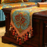 Cette image présente un magnifique chemin de table orné de motifs floraux colorés et de franges dorées, créant une atmosphère luxueuse et élégante.