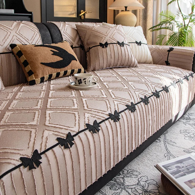 Cette image présente un canapé décoratif avec des coussins et des motifs géométriques texturés en beige et noir, créant une atmosphère élégante et sophistiquée dans le salon.