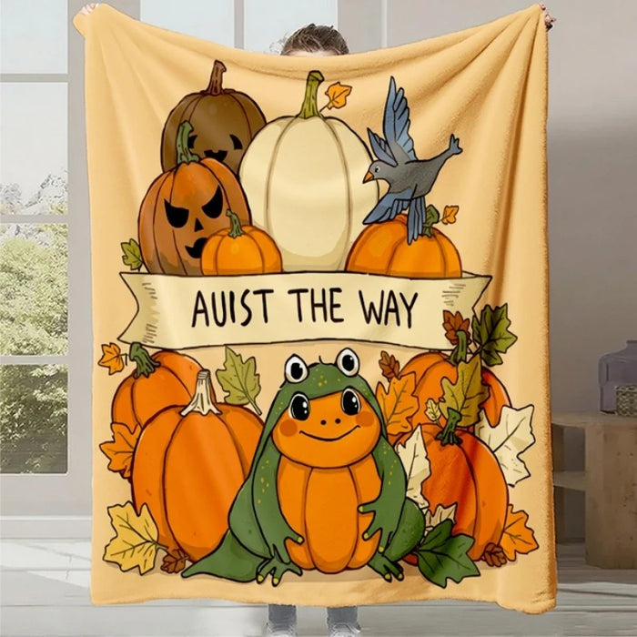 Affichez une couverture confortable en flanelle jaune avec des illustrations automnales colorées d'un personnage de grenouille mignon, de citrouilles, de feuilles et de texte "Avist the way".