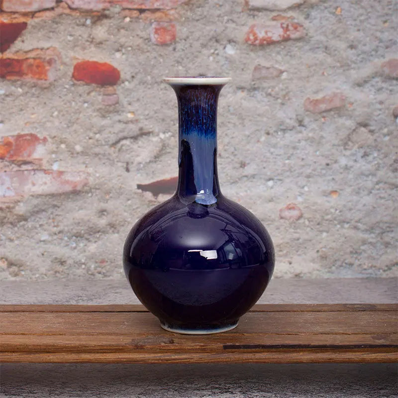 Vase de couleur bleu foncé avec un design élégant, posé sur une surface en bois, créant une ambiance apaisante.