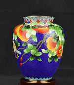 Vase décoratif bleu foncé avec des motifs floraux colorés et des ornements dorés, créant une scène vibrante et élégante.