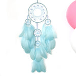 Un capteur de rêves circulaire bleu pâle et blanc décoré de plumes et de perles.
