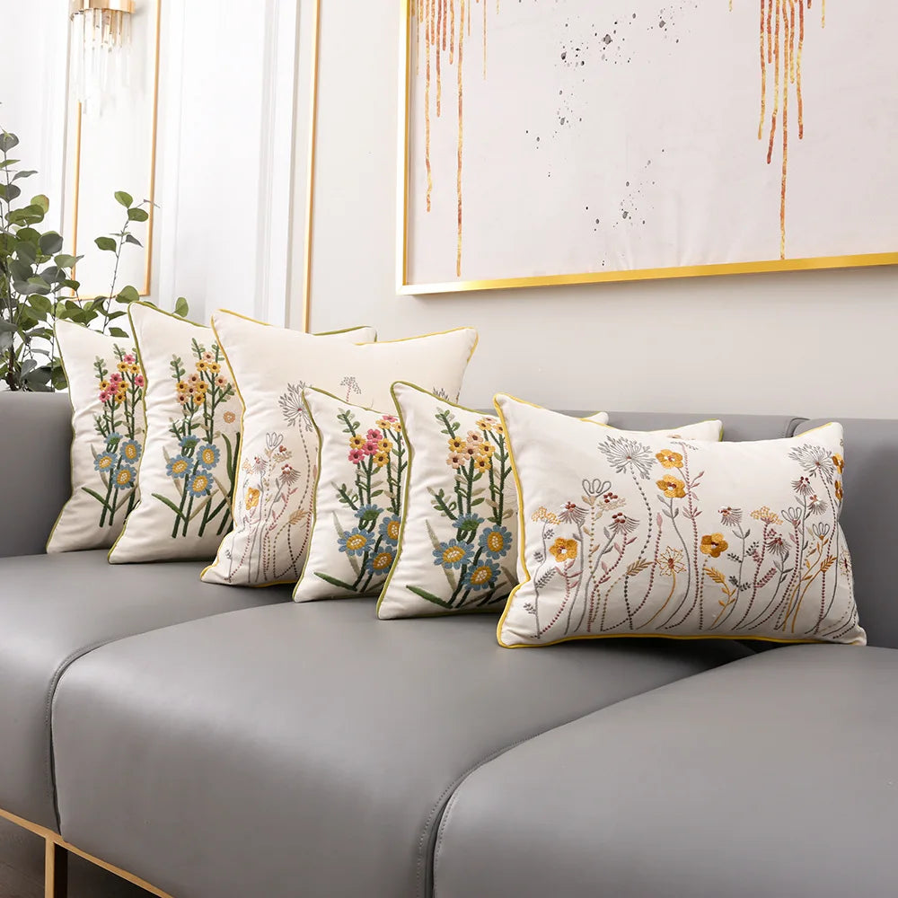 Une pièce élégante et apaisante, avec un canapé gris et des coussins ornés de motifs floraux colorés, créant une atmosphère chaleureuse et invitante.