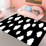 Un tapis moderne avec des nuages blancs sur un fond noir, donnant une ambiance ludique et confortable dans un salon aux tons roses.