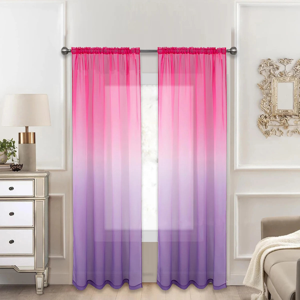 Voilage dégradé du rose au violet encadrant une fenêtre dans un salon élégant aux tons clairs et meubles miroirs.