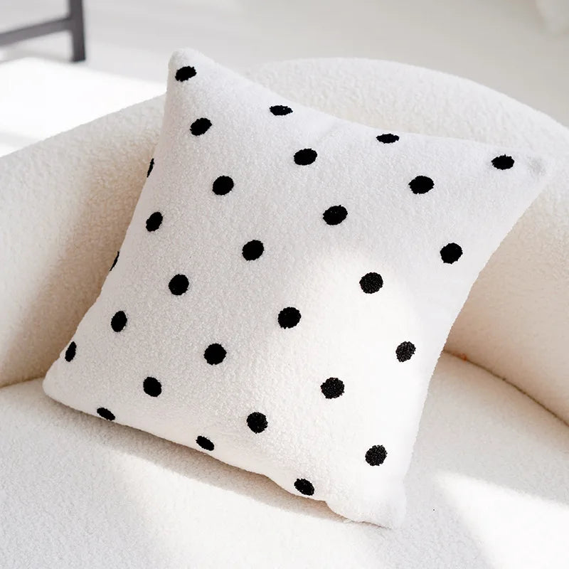 Coussin blanc moelleux à pois noirs, décorant un canapé confortable.