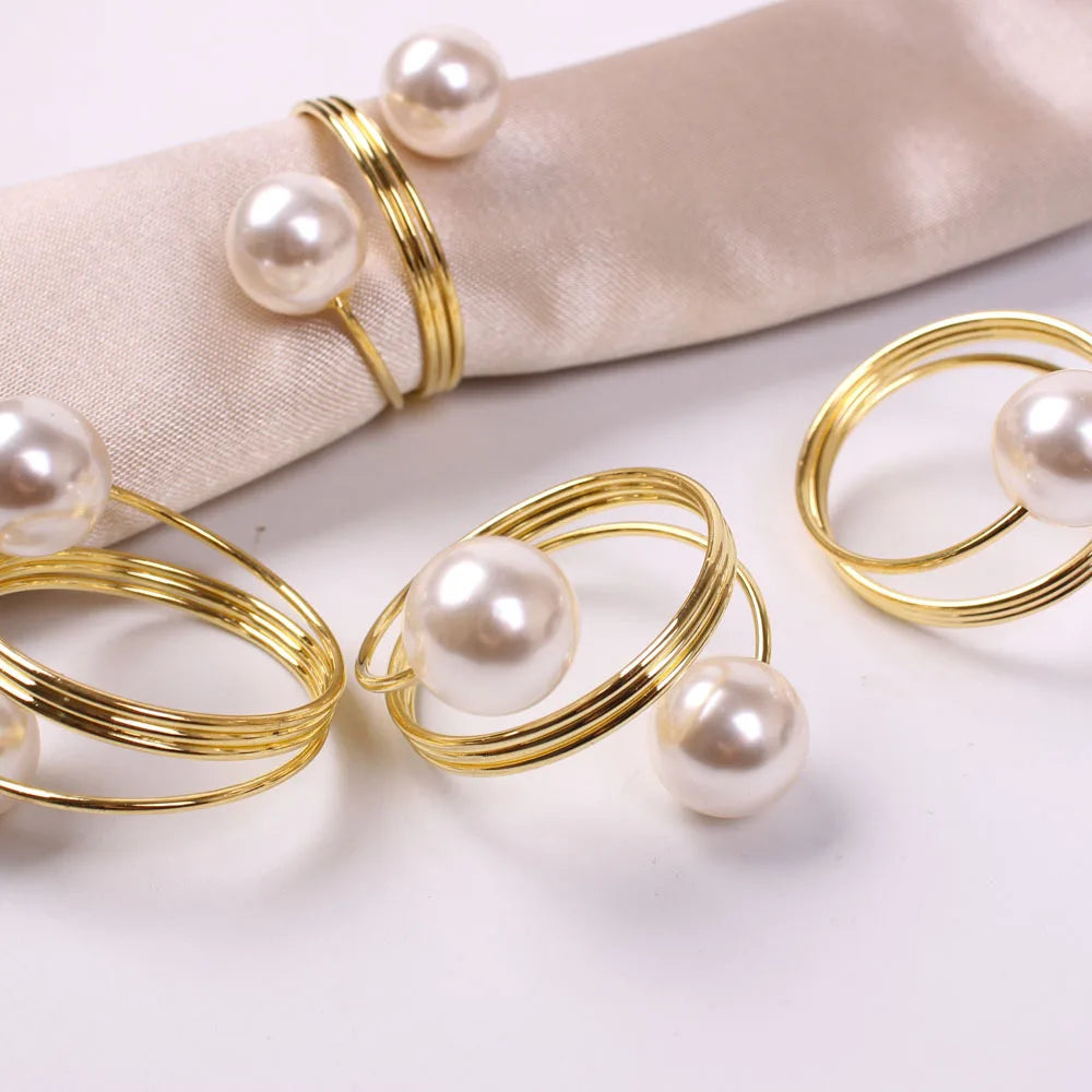Des bijoux en or et perles blanches, disposés de manière élégante sur un tissu beige, offrant une image raffinée et luxueuse.