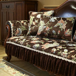 Ce canapé vintage en bois sombre est recouvert d'un tissu fleuri aux couleurs chaudes, rehaussé de délicates dentelles, créant une atmosphère élégante et raffinée dans cette pièce d'intérieur.