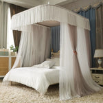 L'image montre un lit avec un baldaquin blanc et des rideaux suspendus, créant un espace douillet et romantique dans une chambre aux meubles élégants.