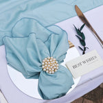 Une belle fleur en soie turquoise ornée de perles et de strass, posée sur une feuille avec une carte d'inscription "Meilleurs voeux".