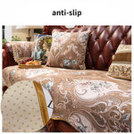 Coussin décoratif avec motifs floraux et paisley sur un canapé en cuir.