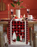 Une table de fête de Noël décorée avec un centre de table festif, des bougies, des verres de cristal et une nappe à motifs de cerfs et de sapins.