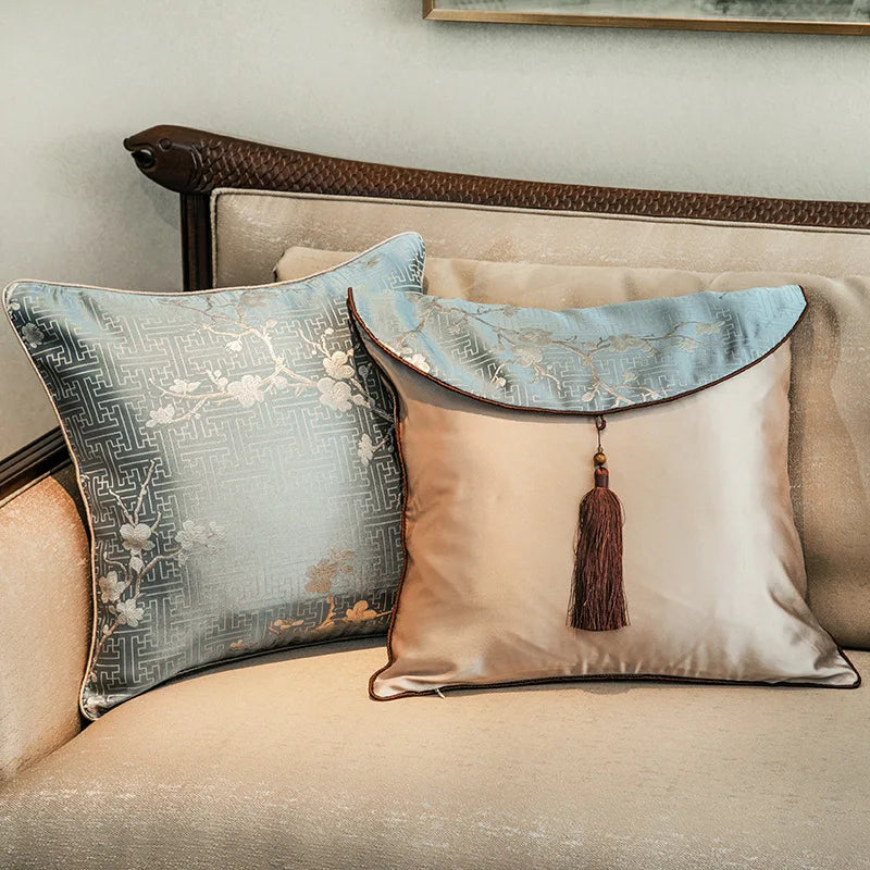 Coussin décoratif élégant aux motifs géométriques et ornements dorés, placé sur un canapé beige, créant une ambiance raffinée.