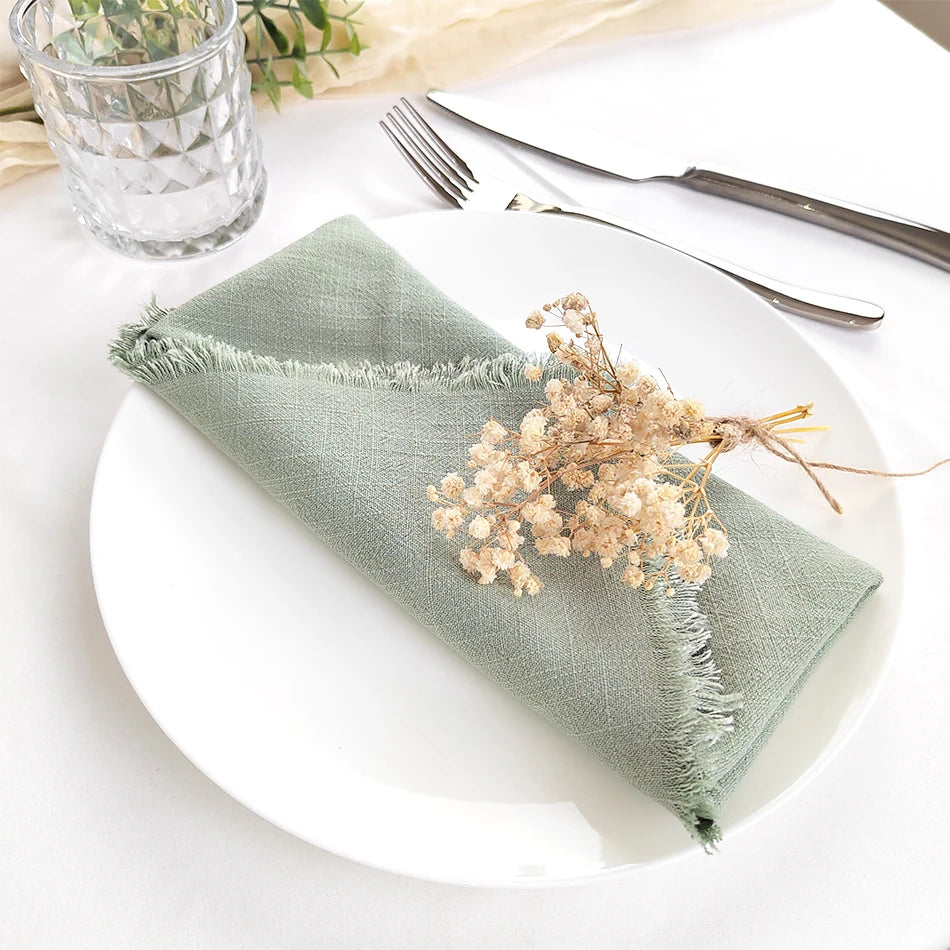 Un élégant arrangement de serviette et de fleurs séchées sur un plat blanc, créant une atmosphère chaleureuse et épurée pour la table.