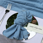 Table élégante avec nappe bleue, couverts et une carte de remerciement "Just for you" sur un plat décoratif.