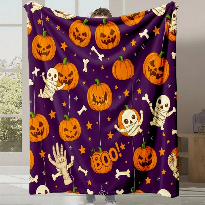 Couverture moelleuse violette avec des citrouilles d'Halloween souriantes, des squelettes et des os blancs sur un motif étoilé.