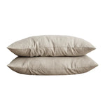 Deux oreillers en lin beige superposés sur fond blanc.