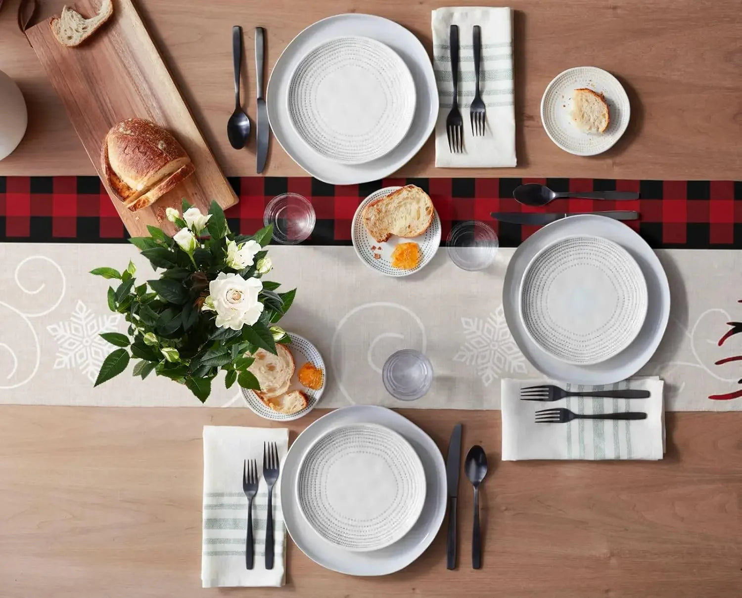 L'image montre une table dressée élégamment, avec de la vaisselle blanche et des accessoires de table coordonnés, des fleurs fraîches, du pain et des éléments décoratifs. Cette composition soignée crée une ambiance conviviale et chaleureuse, prête à accueillir un repas.