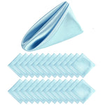 Serviettes pliées en forme de triangle dans des tons bleus et aqua, disposées sur un fond blanc.