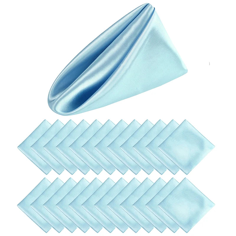 Serviettes pliées en forme de triangle dans des tons bleus et aqua, disposées sur un fond blanc.