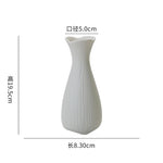 Vase en céramique blanc élégant et épuré avec une forme distinctive.
