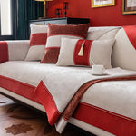 Un canapé confortable avec des coussins rouges et beiges, posé sur un sol en bois, dans une pièce aux murs rouges.