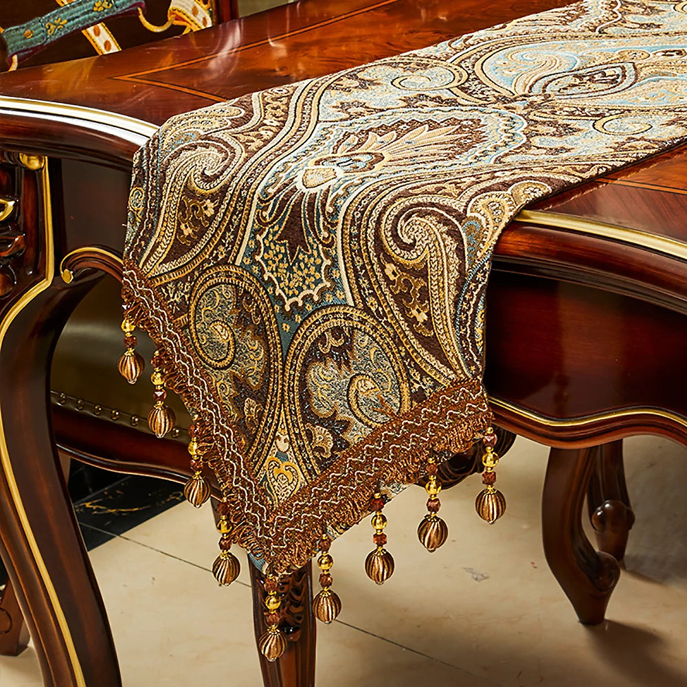 Un riche châle doré aux motifs paisley repose gracieusement sur un meuble de style vintage, créant une atmosphère élégante et raffinée.