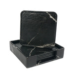 Élégants sous-verres en marbre noir, élégamment rangés dans une boîte assortie, offrant une touche de sophistication à toute table.