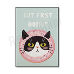 Une image amusante montrant un chat noir et blanc avec de gros yeux sur un beignet rose, avec le texte « But first donut » écrit au-dessus.