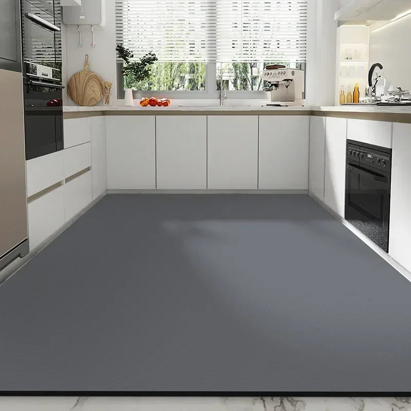 Cuisine moderne avec plan de travail gris et façades blanches, équipée d'un four et d'accessoires sur le rebord de la fenêtre.