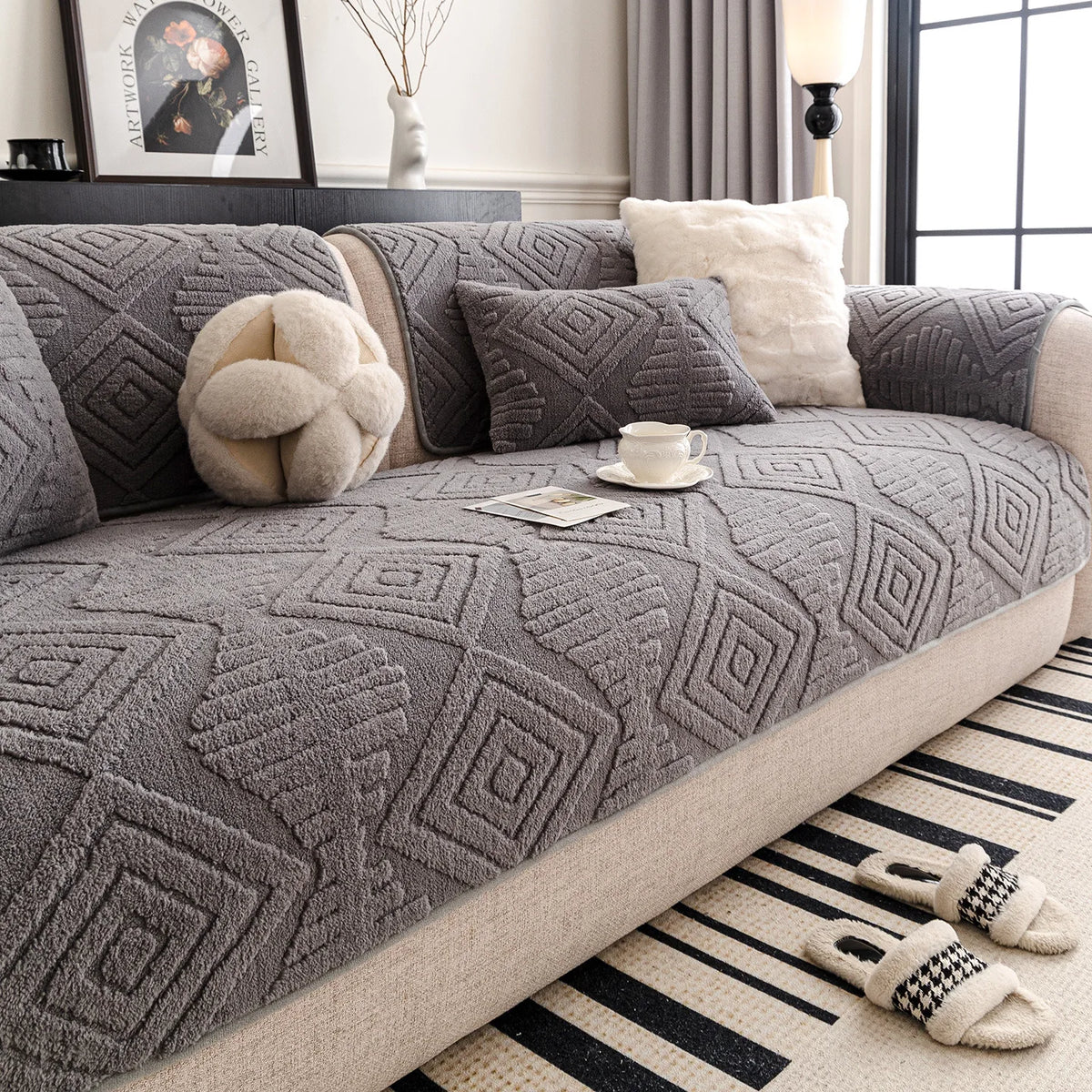 Un salon douillet et élégant avec un canapé recouvert d'un motif géométrique gris et de coussins moelleux, accompagné d'un tapis noir et blanc rayé, créant une ambiance chaleureuse et confortable.