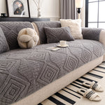 Un salon douillet et élégant avec un canapé recouvert d'un motif géométrique gris et de coussins moelleux, accompagné d'un tapis noir et blanc rayé, créant une ambiance chaleureuse et confortable.