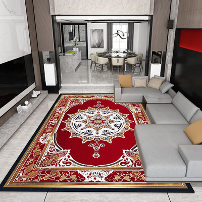 Tapis d'intérieur aux motifs floraux rouges et dorés sur un sol en carrelage blanc, entouré de canapés gris et d'un mobilier moderne dans une salle à manger ouverte.