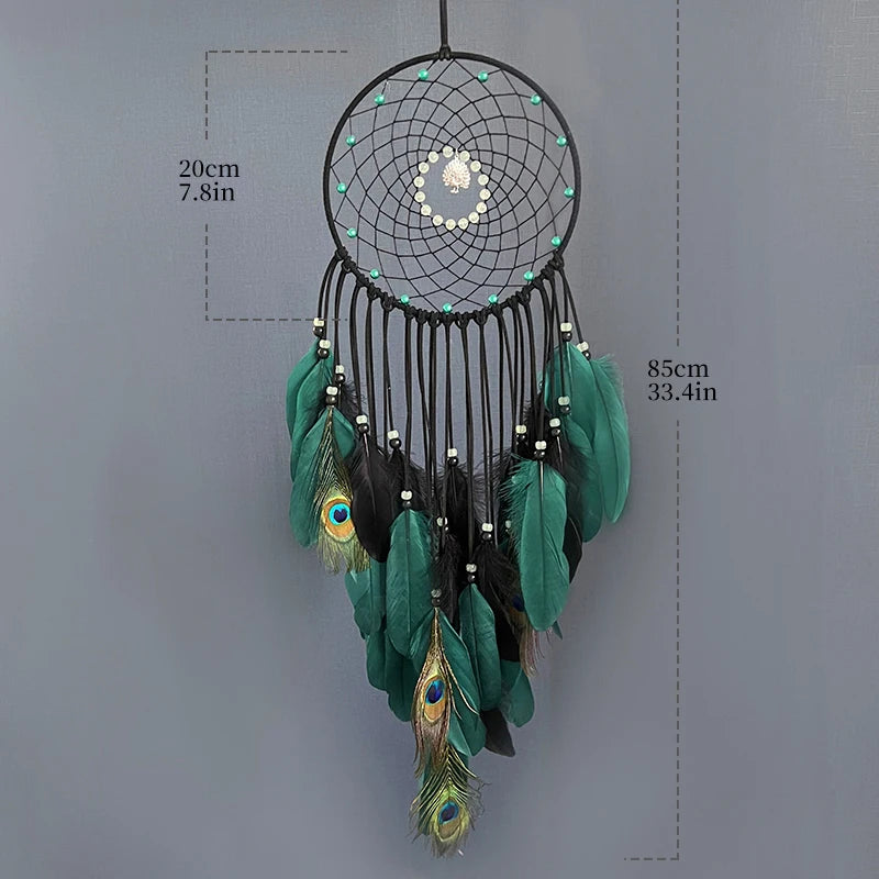 Un capteur de rêves orné de plumes de paon vertes et noires, de perles et de plumes décoratives, suspendu par un anneau en métal noir.