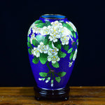 Vase bleu et vert avec des fleurs blanches, créé avec des motifs élégants et un style artistique.
