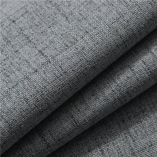 Gros plan sur un tissu gris en polyester effet lin, à la trame visible et à la texture épaisse, utilisé pour les rideaux.