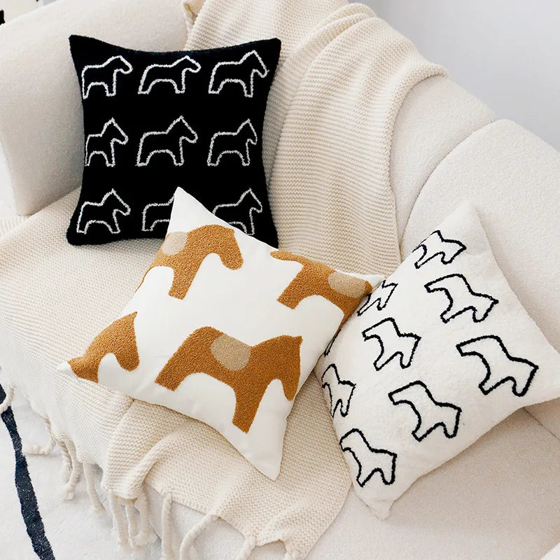 Cette image montre des coussins décoratifs avec des motifs d'animaux, ainsi qu'une couverture blanche en tricot, créant une atmosphère confortable et douillette.