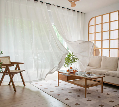 Voilage blanc opaque flottant dans un salon lumineux avec mobilier en bois clair et décoration naturelle.