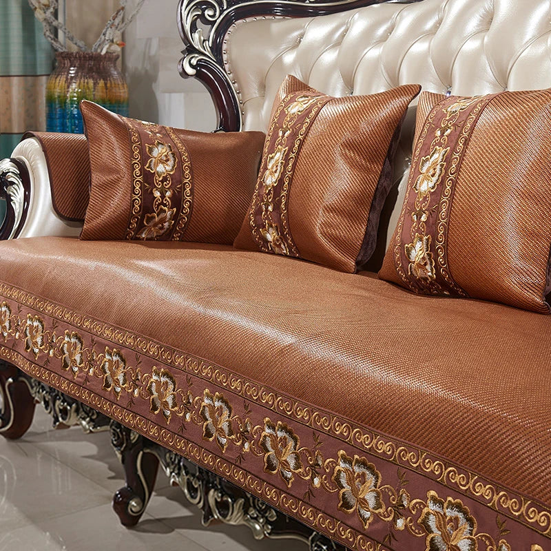 Canapé orné de motifs floraux dorés sur un fond en cuir marron, avec des coussins assortis, créant une ambiance élégante et chaleureuse dans le salon.