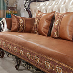 Canapé orné de motifs floraux dorés sur un fond en cuir marron, avec des coussins assortis, créant une ambiance élégante et chaleureuse dans le salon.